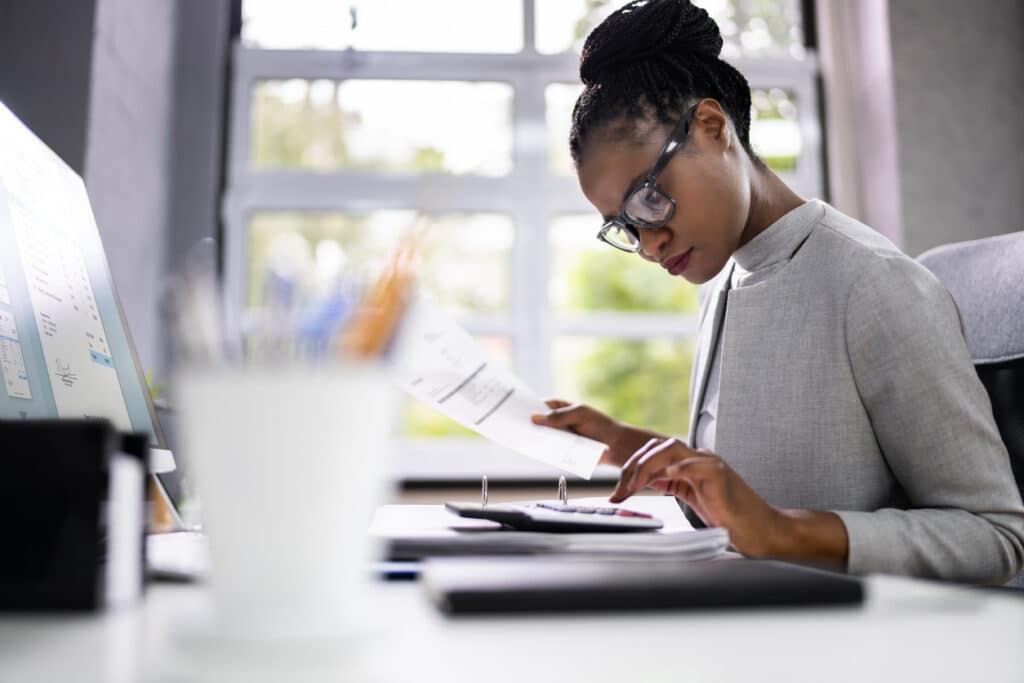 Accountant using a calculator, working through treaty-related tax reporting that may require Form 8833.