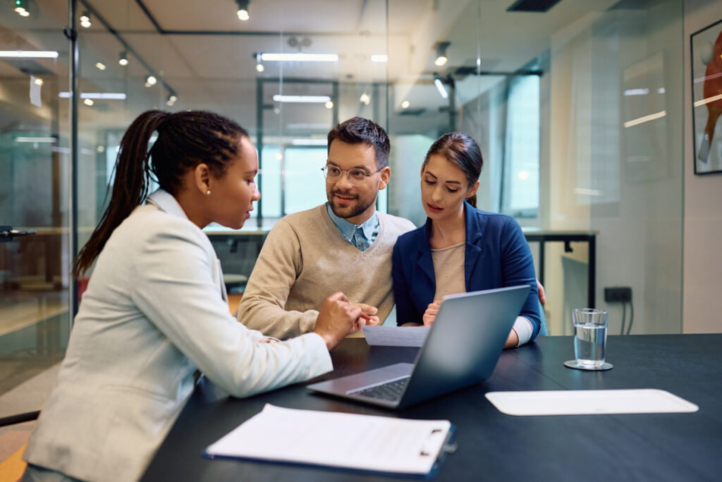 Young couple reviewing documents with a financial advisor, discussing reporting requirements for Form 8938.