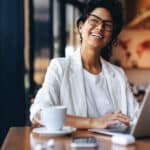Businesswoman working remotely in a cozy café, representing cross-border professionals whose income may be affected by tax treaties.