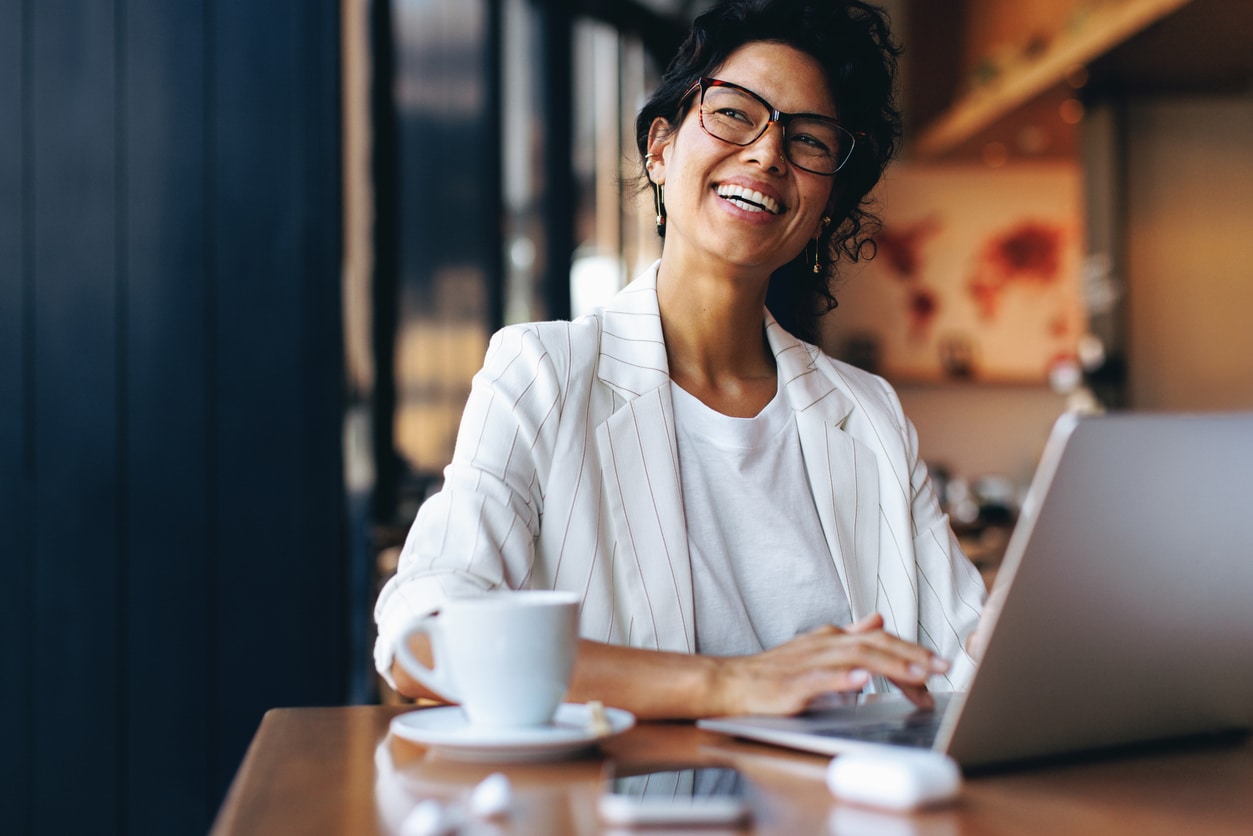 Businesswoman working remotely in a cozy café, representing cross-border professionals whose income may be affected by tax treaties.
