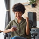 Woman reacting excitedly to something on her phone, capturing the kind of unexpected gift or foreign transfer that may require Form 3520.