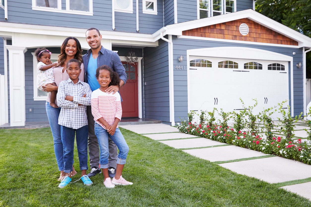 Happy family standing outside their home abroad, representing expats who may qualify for the foreign housing deduction.