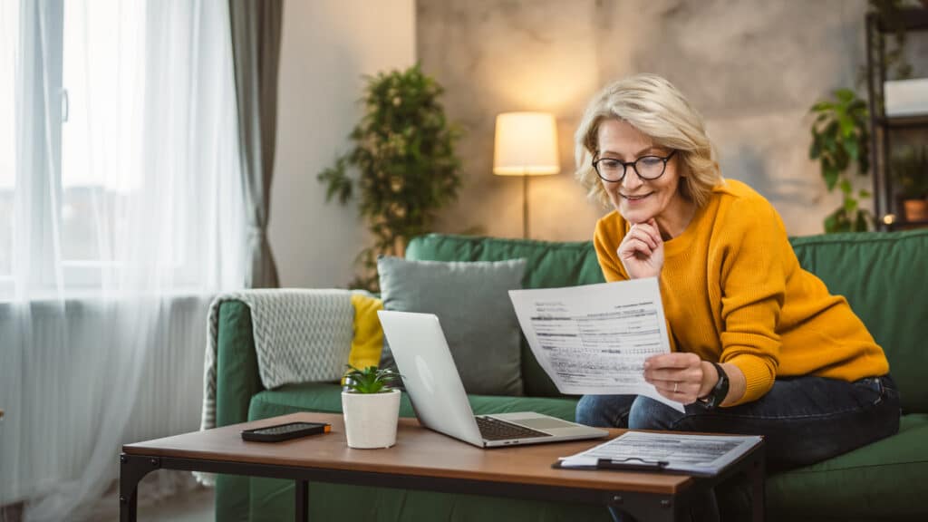 Mature woman working on her laptop at home, reviewing healthcare coverage exemptions that may require Form 8965.