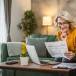 Mature woman working on her laptop at home, reviewing healthcare coverage exemptions that may require Form 8965.