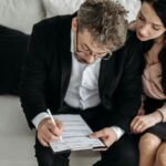 A man and a woman sat in a couch filling out a form