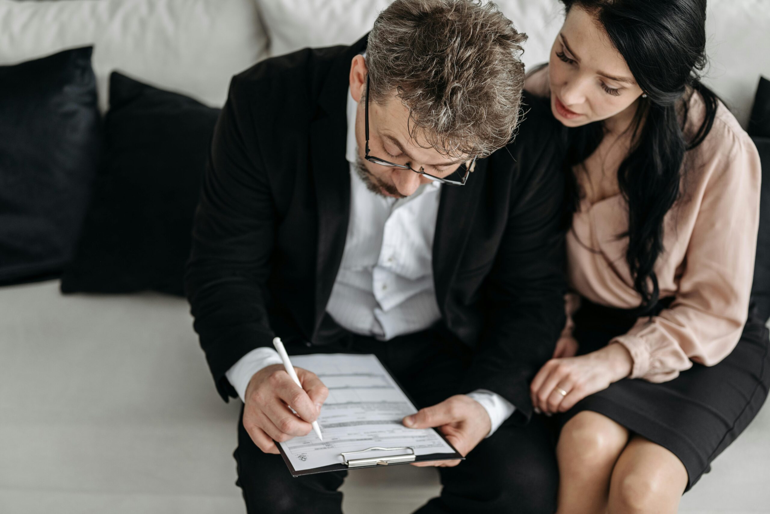 A man and a woman sat in a couch filling out a form