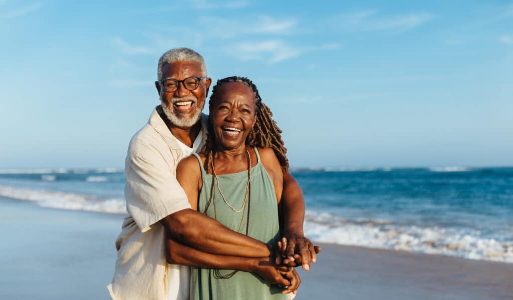 Joyful retired couple walking along the beach, symbolizing the extended filing timeline offered by Form 2350 for expats.