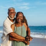 Joyful retired couple walking along the beach, symbolizing the extended filing timeline offered by Form 2350 for expats.