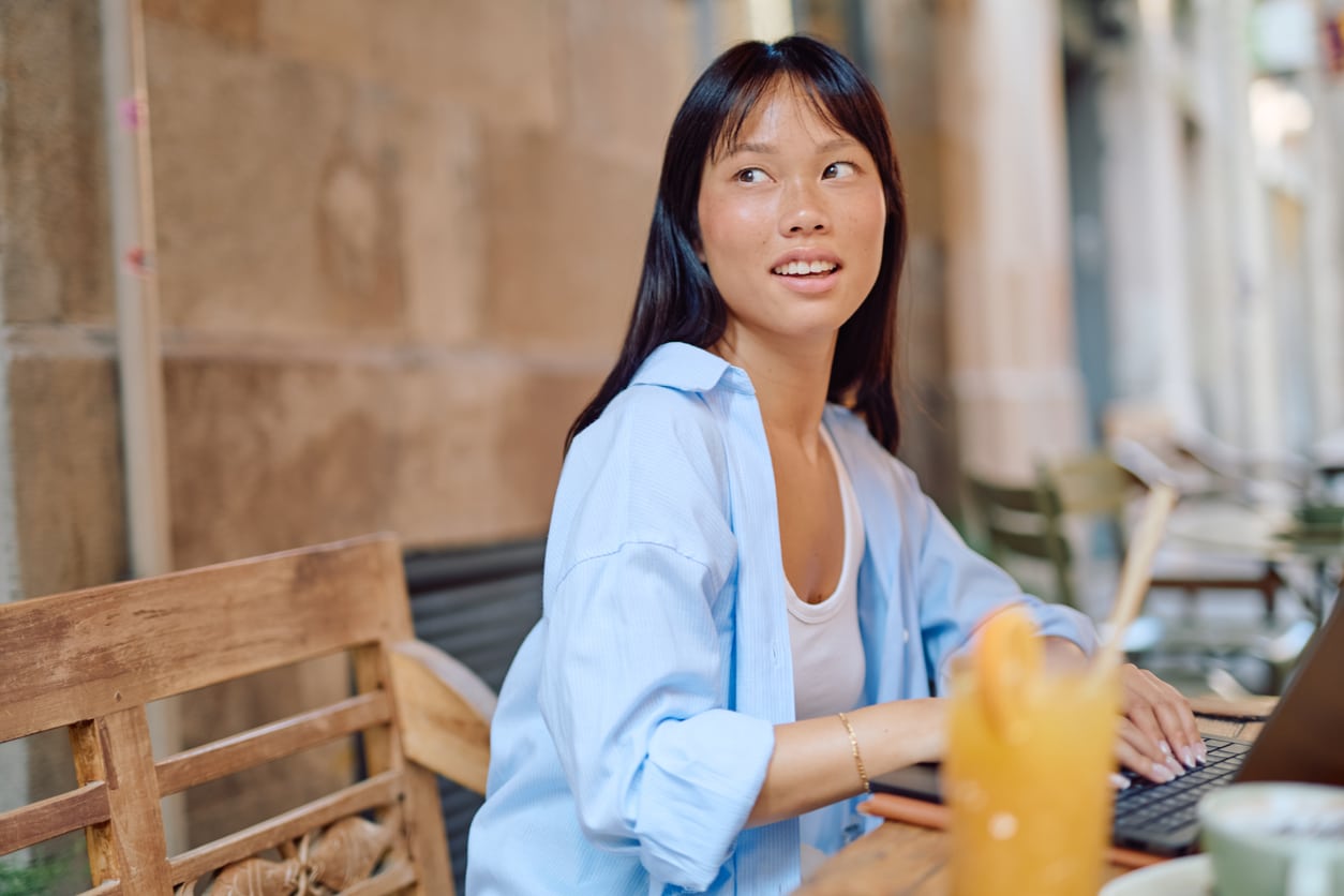 Young woman working on a laptop at an outdoor café, representing the flexible work life often tied to self employment tax deductions.