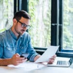 Focused entrepreneur reviewing financial documents and tax returns, possibly dealing with the consequences of FBAR penalties.