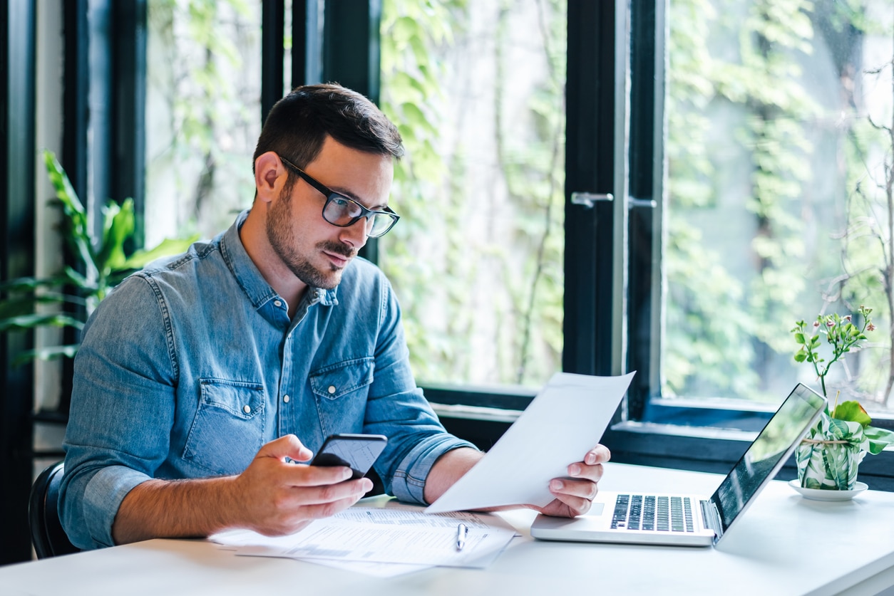Focused entrepreneur reviewing financial documents and tax returns, possibly dealing with the consequences of FBAR penalties.