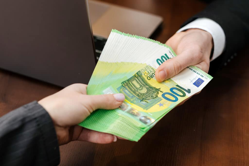 Cash being handed across an office desk, symbolizing financial transactions that can raise broader questions around FBAR filing.