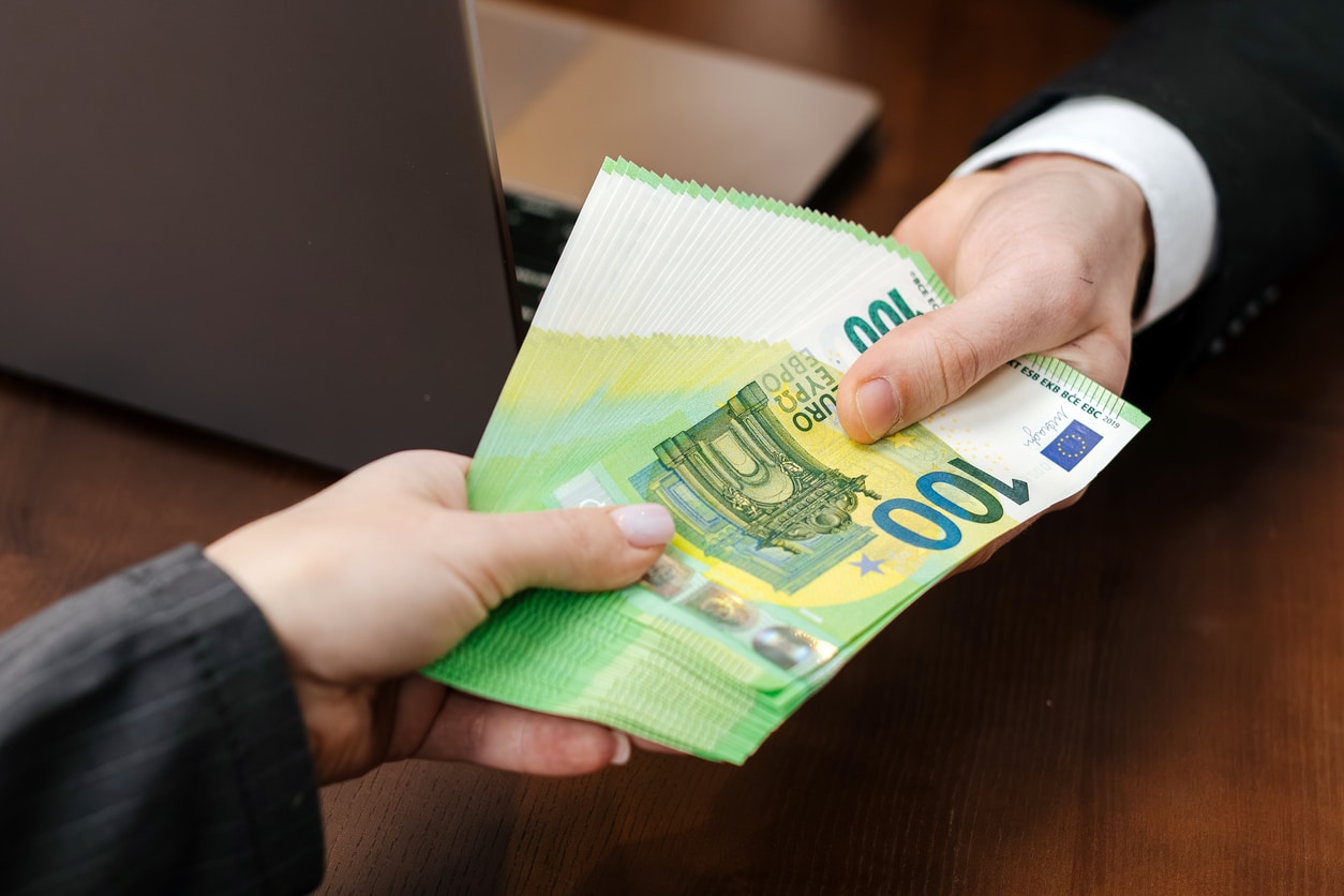 Cash being handed across an office desk, symbolizing financial transactions that can raise broader questions around FBAR filing.