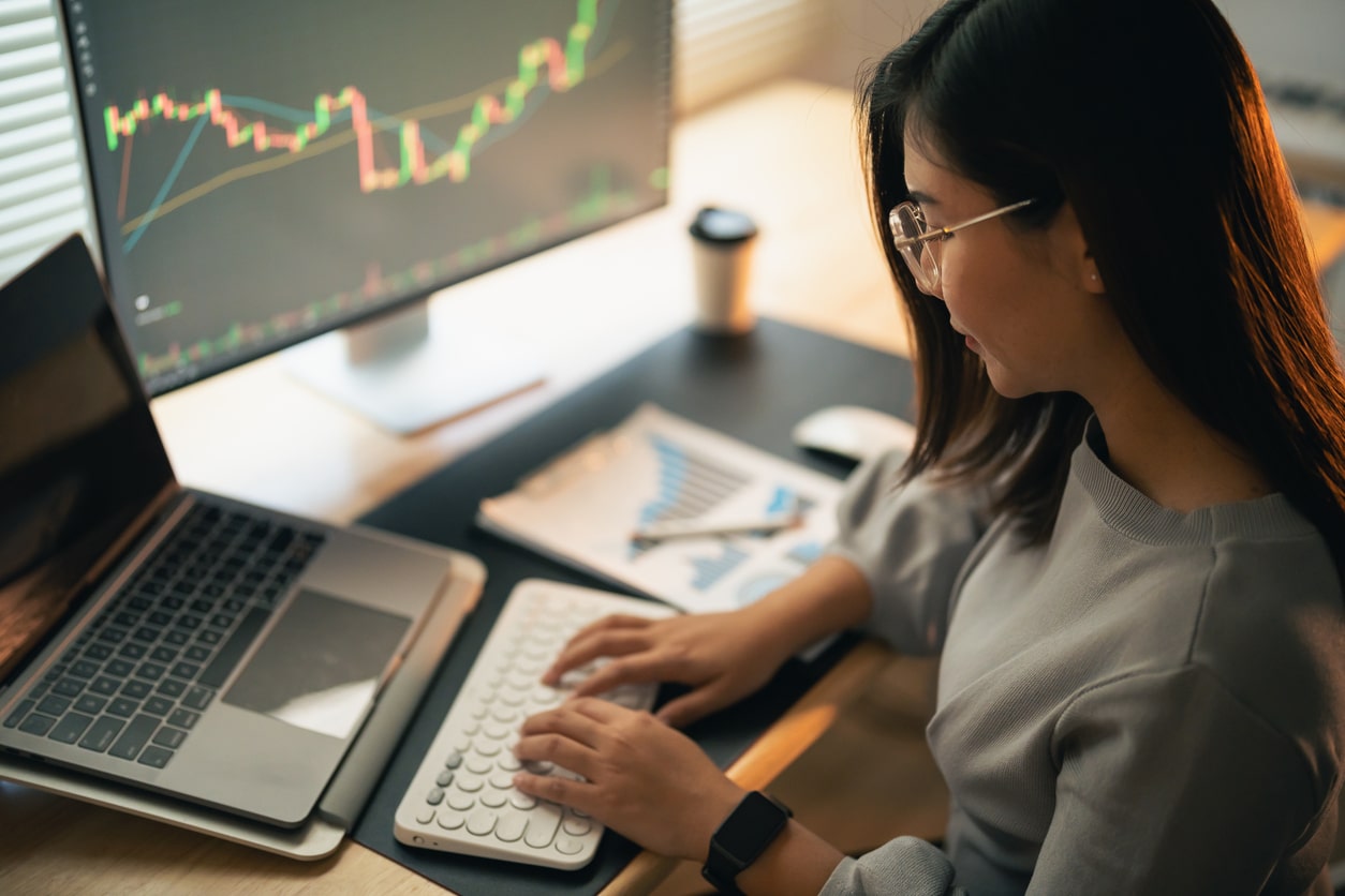Investor reviewing market charts, preparing to report capital gains and losses on Form 8949.