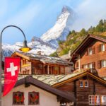 The Swiss flag hanging in a small village square with the Matterhorn rising in the background.