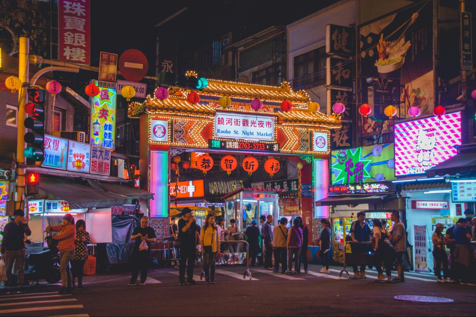 Image of the Taiwan Night Market at night, with neon lights and full of people