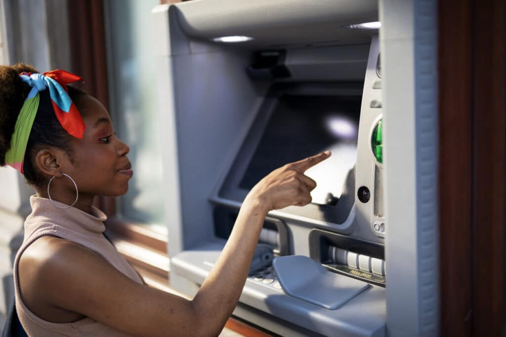 Young woman using an ATM, a reminder that foreign bank accounts like this may need to be reported under FBAR.