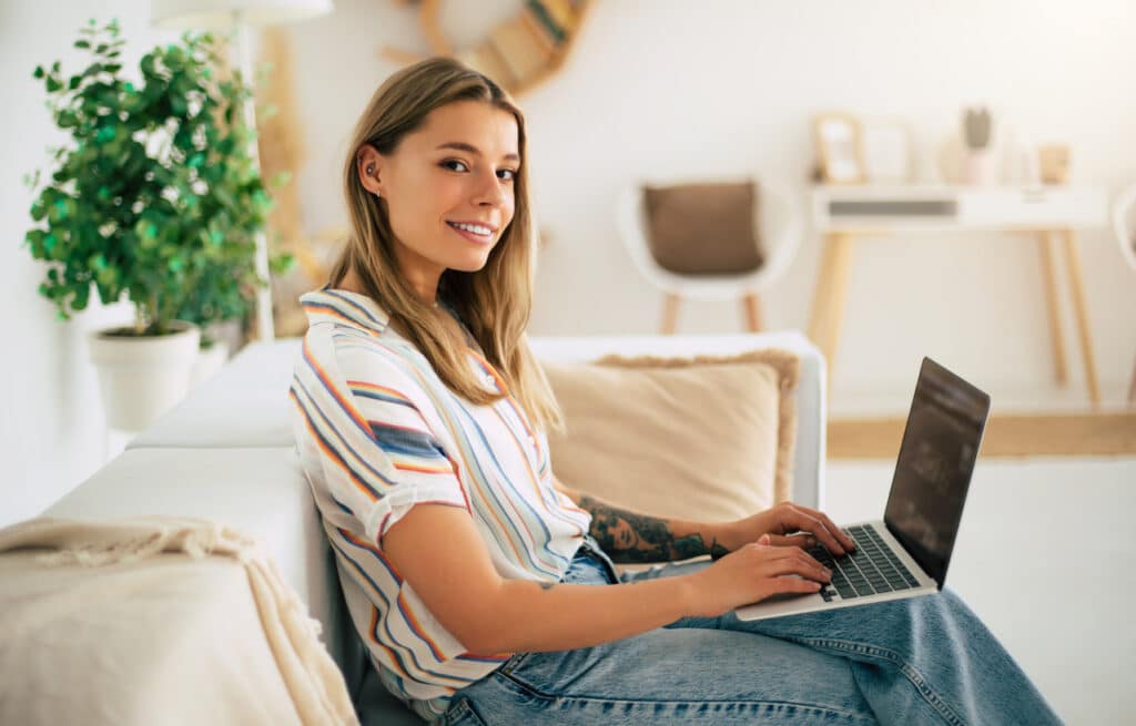 Smiling woman working from home, tracking travel days and eligibility for the physical presence test.