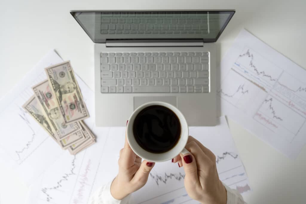 Freelancer counting U.S. dollars beside a laptop and charts, reflecting the currency conversions often needed when using IRS exchange rates.