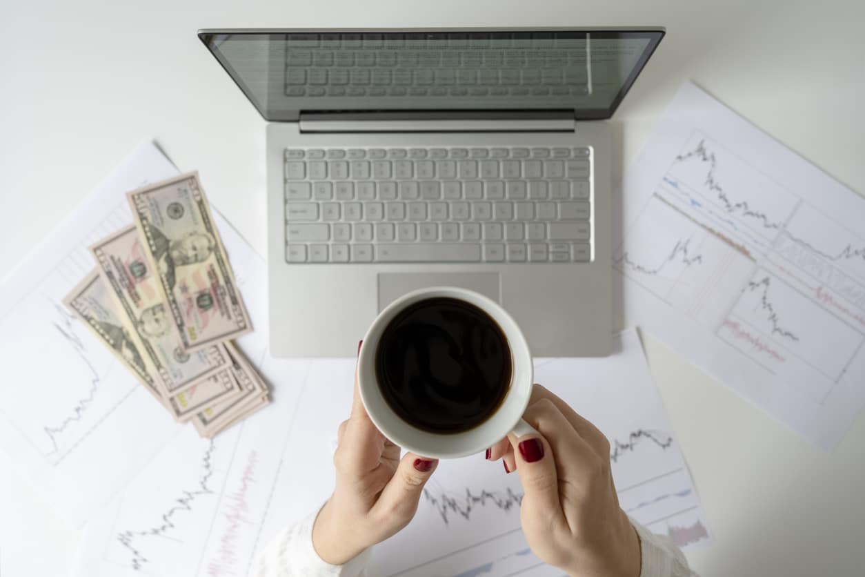 Freelancer counting U.S. dollars beside a laptop and charts, reflecting the currency conversions often needed when using IRS exchange rates.