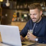 Young man using a laptop in a café, handling personal finances that may involve gift tax reporting.