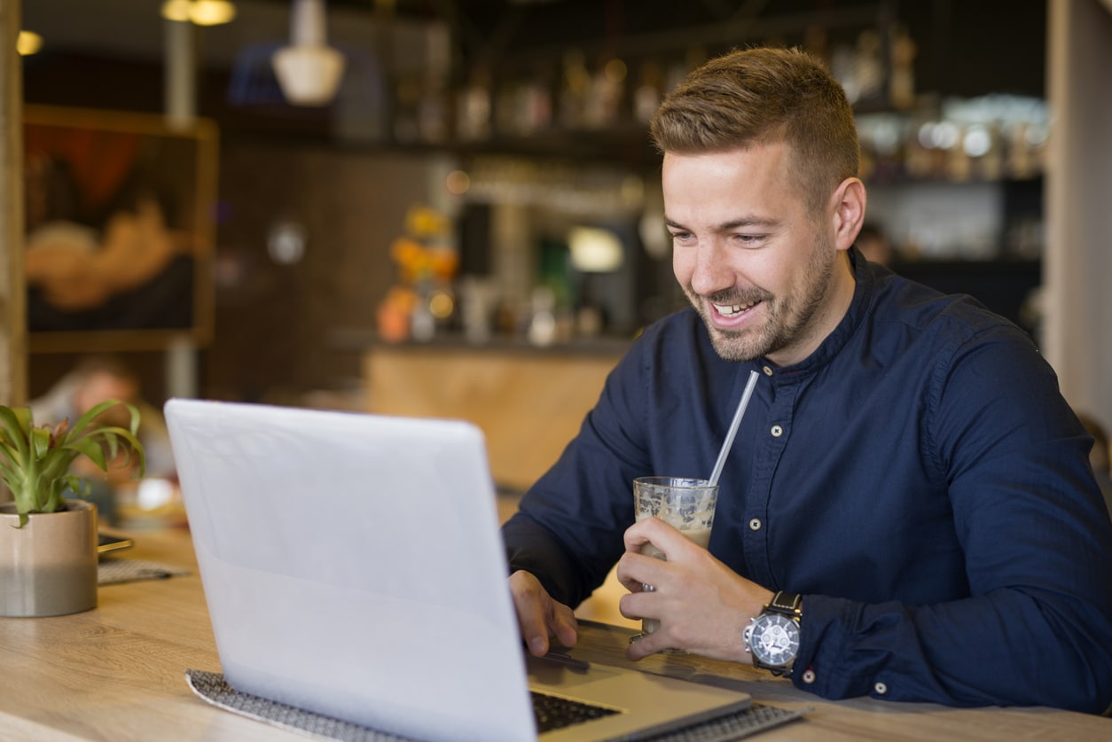 Young man using a laptop in a café, handling personal finances that may involve gift tax reporting.