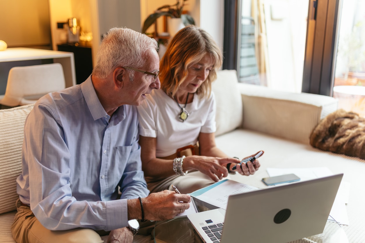 Senior couple reviewing finances with a calculator and laptop, reflecting the kind of foreign account reporting that may require FinCEN Form 114.