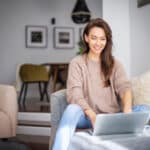 Woman using a laptop on the sofa, preparing to file Form 1040.