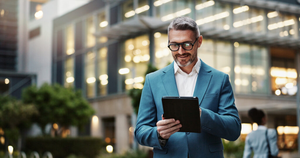 Mature businessman using a tablet outdoors, looking into whether he qualifies for FATCA exemptions while living abroad.