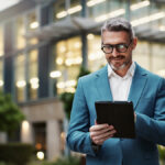 Mature businessman using a tablet outdoors, looking into whether he qualifies for FATCA exemptions while living abroad.