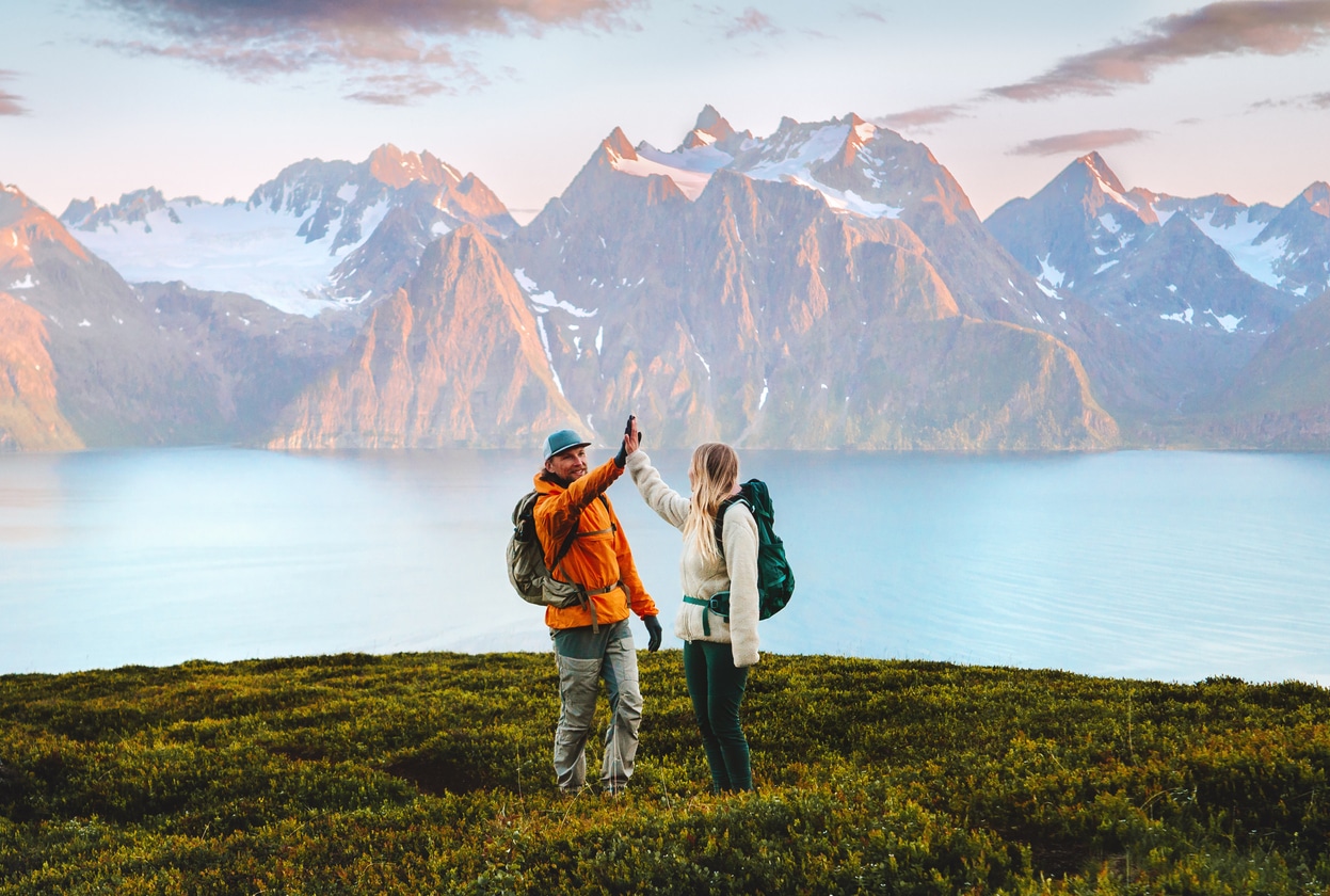 Hiking couple high-fives on a mountain summit, representing the reward of navigating complex filings like Form 1116 for the foreign tax credit.