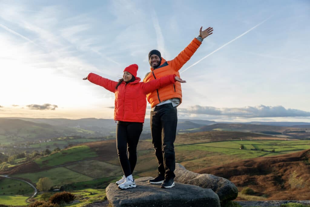 Couple celebrating together on a scenic hilltop, capturing the security and shared future supported by spousal Social Security benefits.