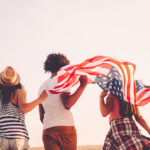 Friends holding an American flag, celebrating as US persons overseas.