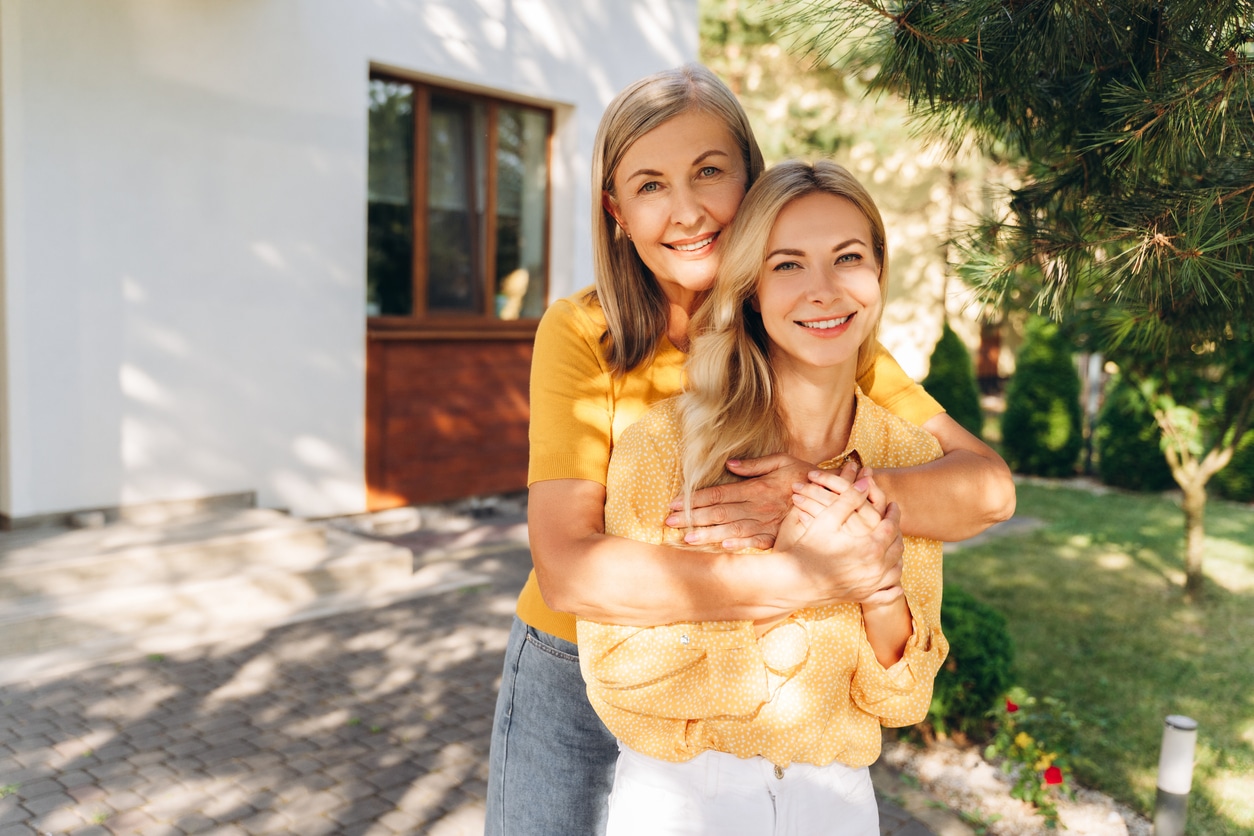 Senior mother and her adult daughter sharing a joyful hug, reflecting the family emotions that can surround selling inherited property.