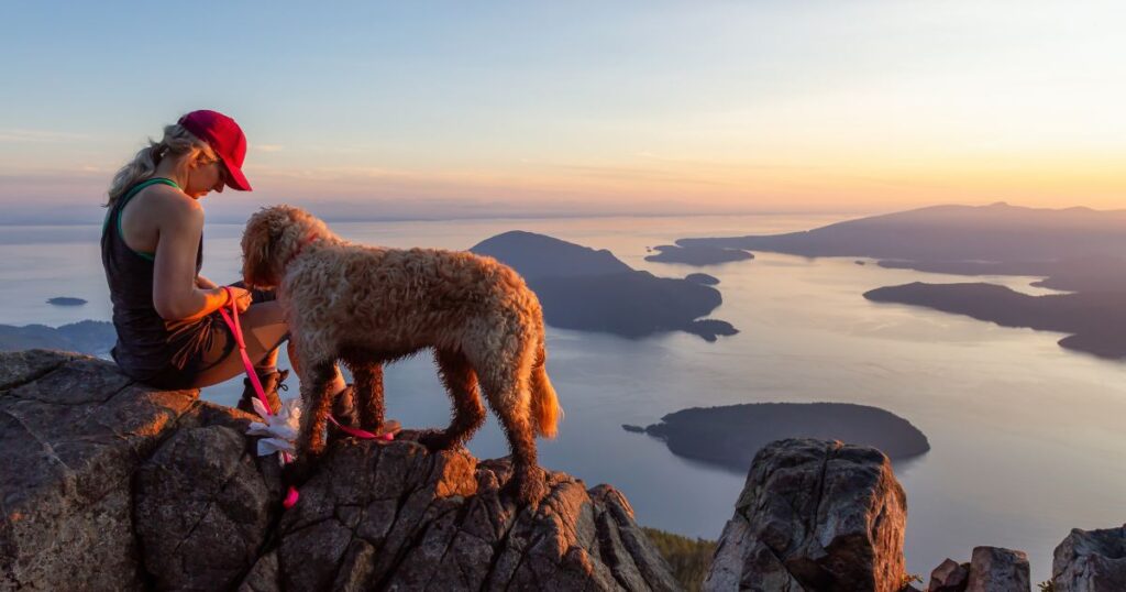 Woman in Canada on a mountain summit with her dog