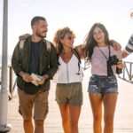 A group of four digital nomads walking along a pier in the sun