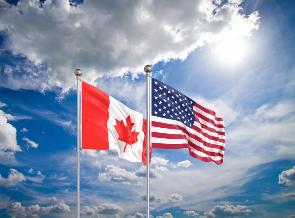 Waving Canadian and American flags side by side, representing the financial comparison of Canada tax rate vs US.