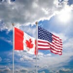 Waving Canadian and American flags side by side, representing the financial comparison of Canada tax rate vs US.