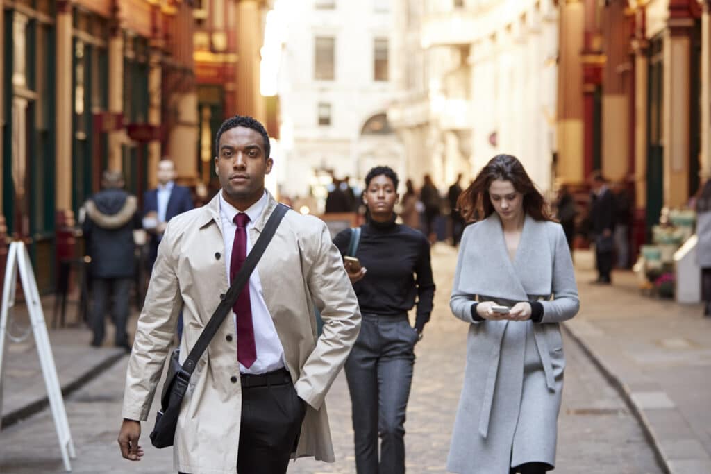 Young professionals walking along a London street, capturing the pace of life for a US citizen working in the UK.