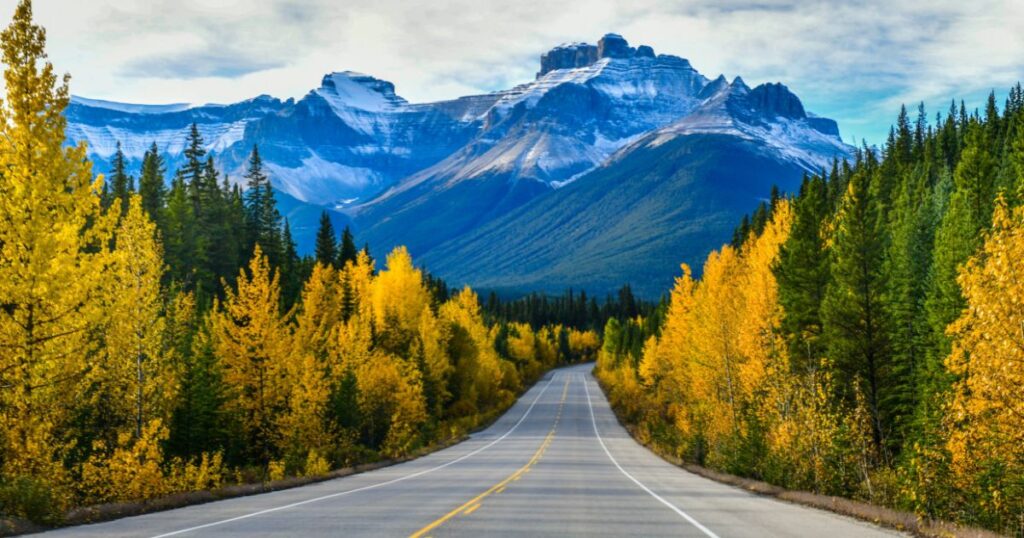 Empty road in Canada with mountains rising in the background.