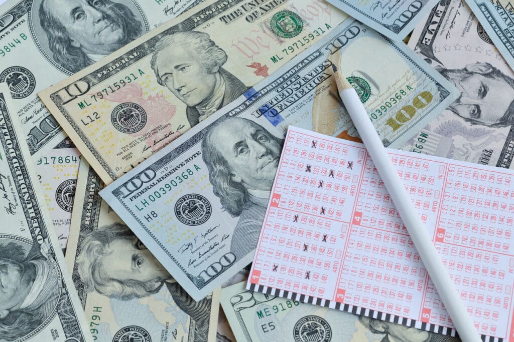 Lottery ticket on top of U.S. dollars, a reminder that taxes on lottery winnings can significantly reduce your payout.