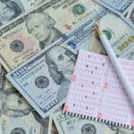 Lottery ticket on top of U.S. dollars, a reminder that taxes on lottery winnings can significantly reduce your payout.