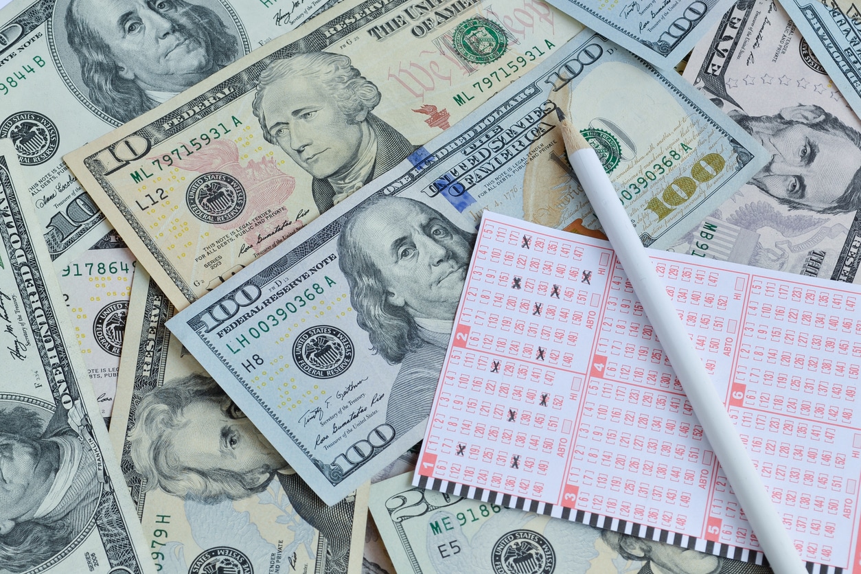 Lottery ticket on top of U.S. dollars, a reminder that taxes on lottery winnings can significantly reduce your payout.
