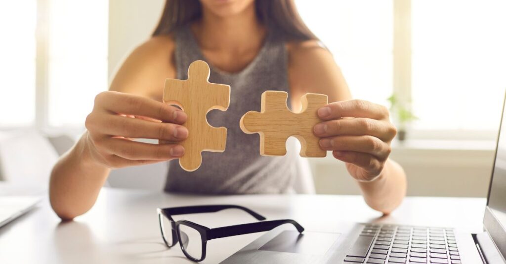 Woman holds two pieces of a jigsaw puzzle together, representing how FBAR vs 8938 apply to US expat taxes.