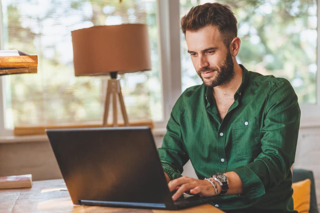 Stressed young man working on a laptop, capturing the pressure of wondering what happens if you miss the tax deadline.