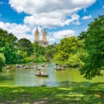 Central Park lake with rowboats and the Manhattan skyline, representing everyday life in a place shaped by New York State income taxes.