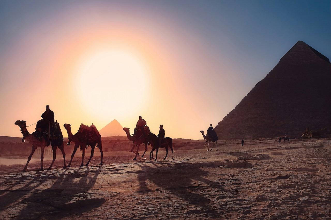 Camel riders pass the pyramids—historic views that are part of daily life for Americans living in Egypt.