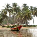 A red boat floats near palm-lined shores, reflecting the coastal life enjoyed by Americans living in Ghana.