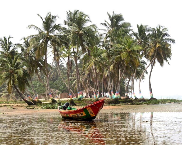 A red boat floats near palm-lined shores, reflecting the coastal life enjoyed by Americans living in Ghana.