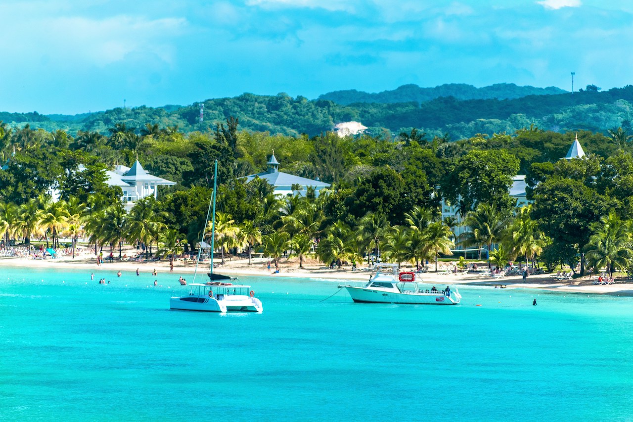 Boats drift on clear water near Negril, capturing the laid-back lifestyle of Americans living in Jamaica.